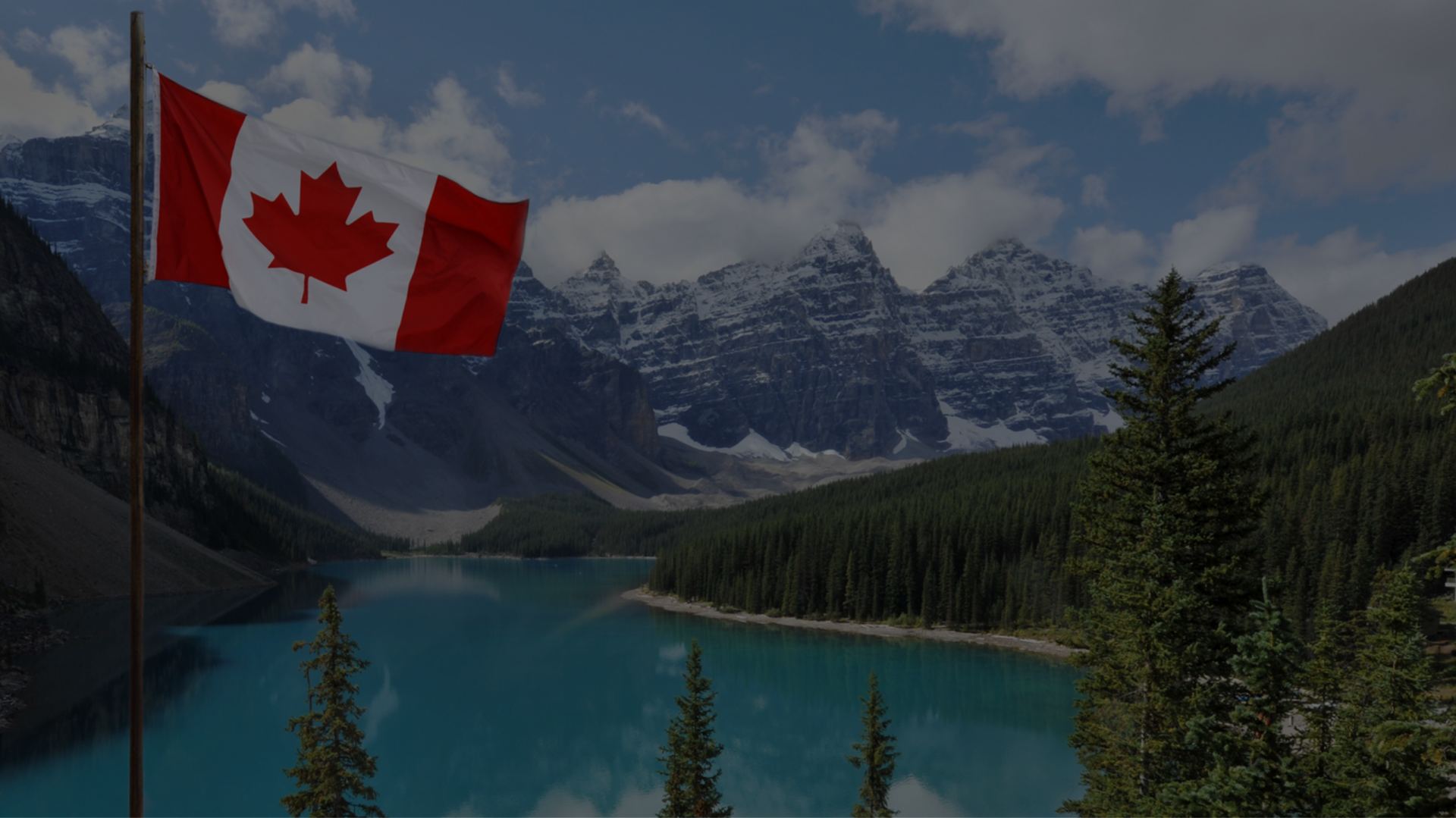 Canadian flag beside a mountain lake in the Canadian Rockies